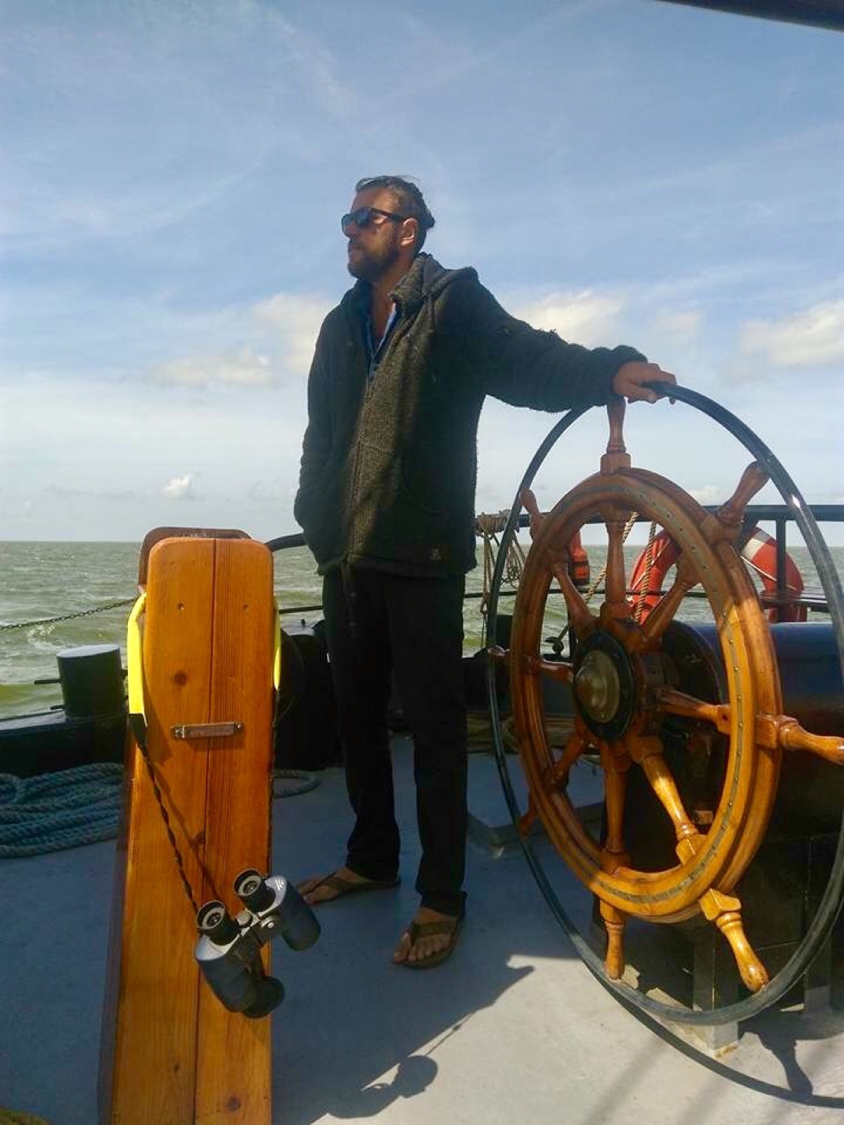Fabio Andreatta steering a traditional vessel barefoot at the helm