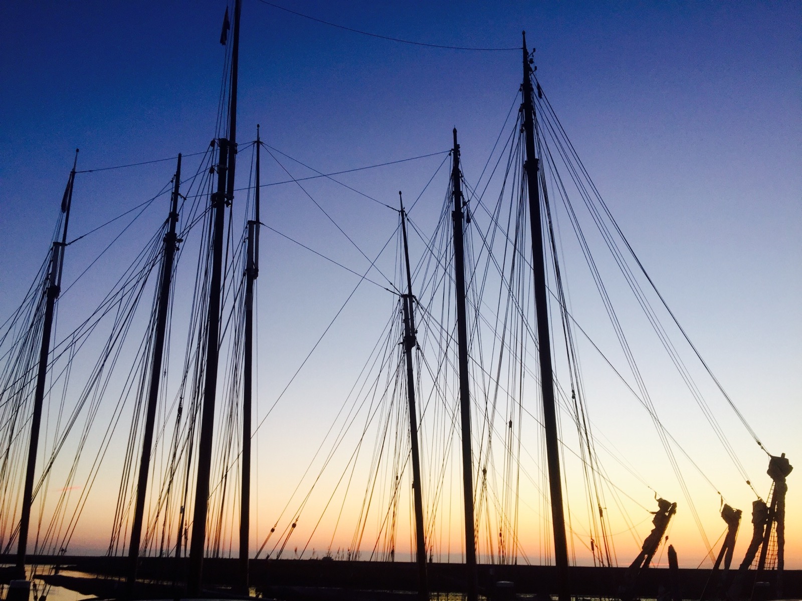 Traditional sailing ship masts silhouetted at sunset in harbour